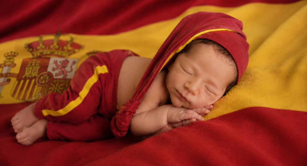 Fotografía de recién nacido dormido, primeros días de vida, envuelto en los colores de España